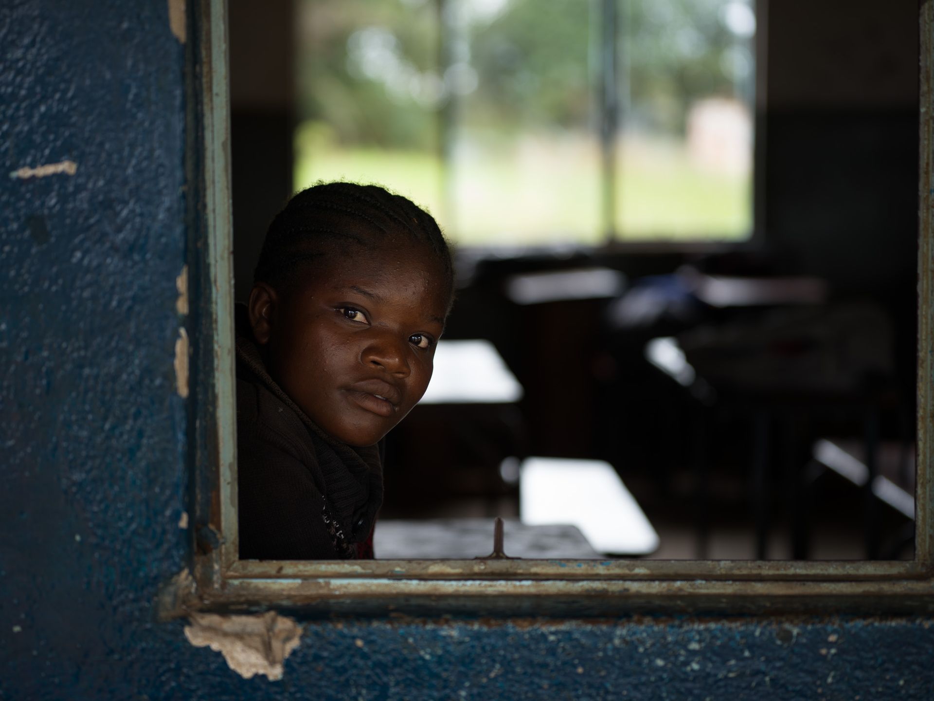 A girl looks through a classroom window, Zambia
